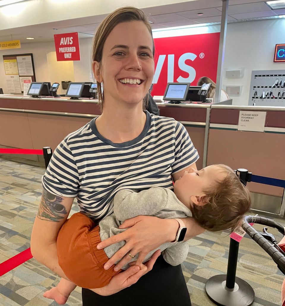 Mother holding sleeping son as they travel through the airport 